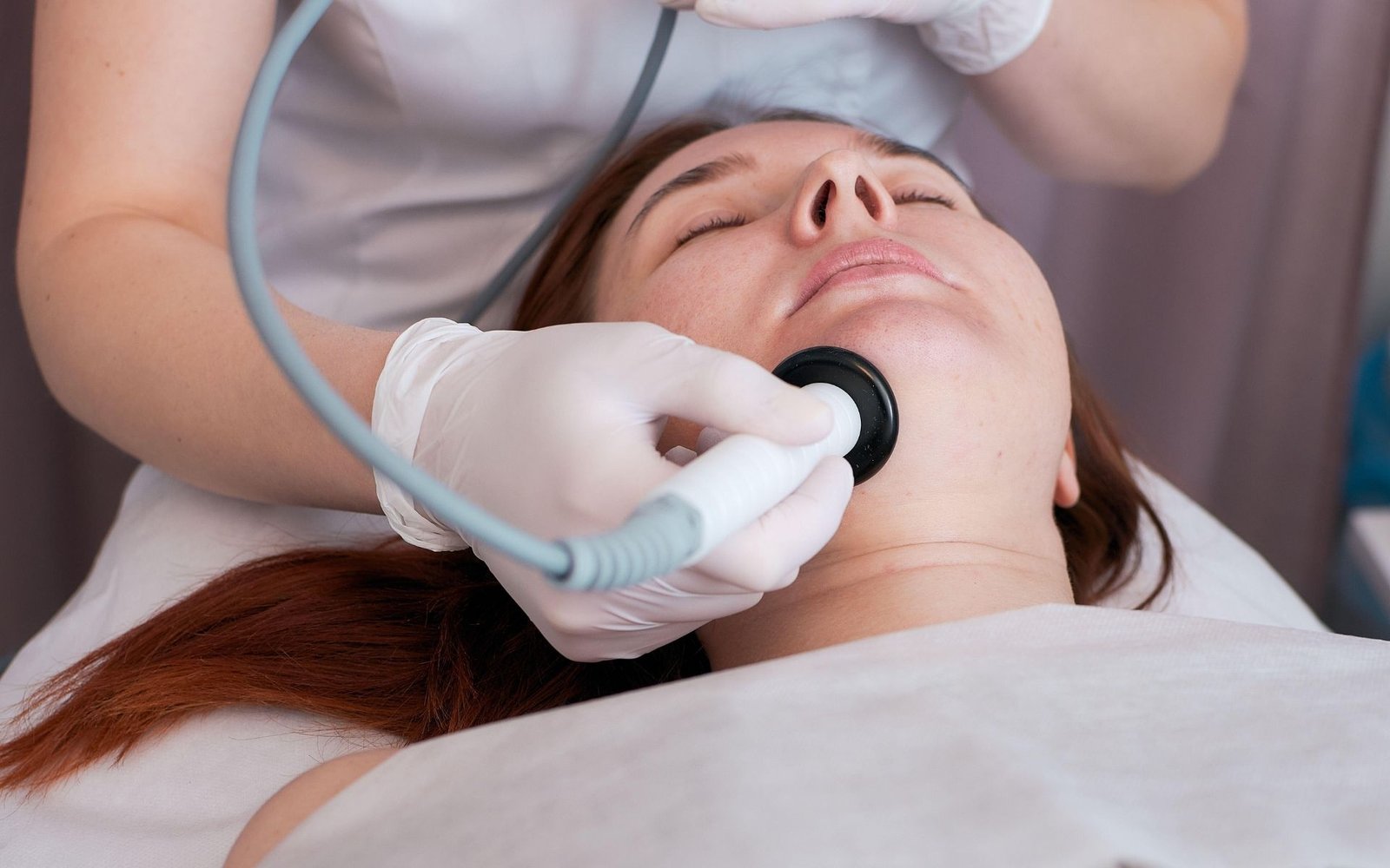 Klinik ortamında bir hastaya cihaz ile tedavi uygulayan doktor, jinekolojide lazer ve radyo frekans teknolojileri temsili görseli